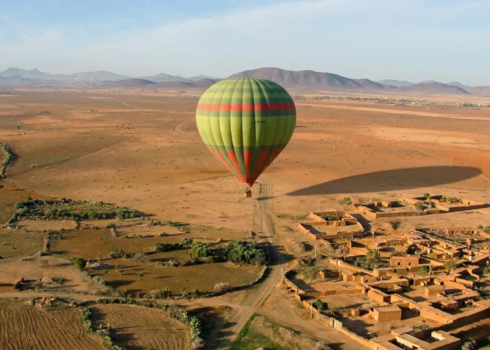 Hot air balloon flying over desert landscape near Marrakech during sunrise