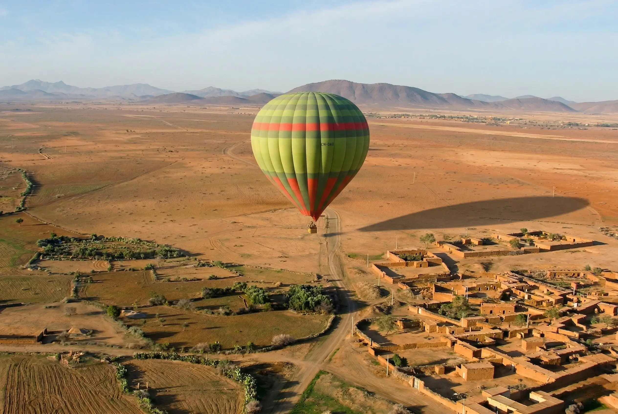 Hot air balloon flying over desert landscape near Marrakech during sunrise