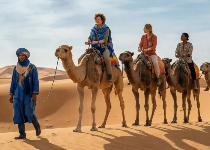 Camel caravan with travelers crossing the Erg Chebbi dunes in Merzouga during a 3 days Marrakech to Merzouga desert tour