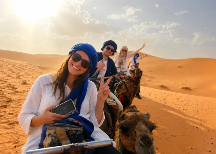 Travelers enjoying camel trekking in the Erg Chebbi dunes during a 6 days Marrakech to Merzouga desert tour