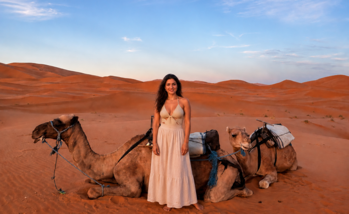 Woman with camels in the Merzouga Sahara Desert at sunset