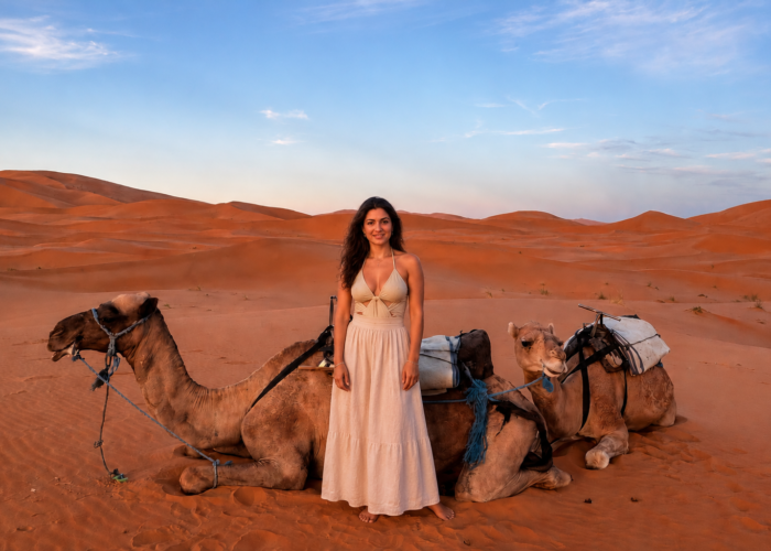Woman with camels in the Merzouga Sahara Desert at sunset