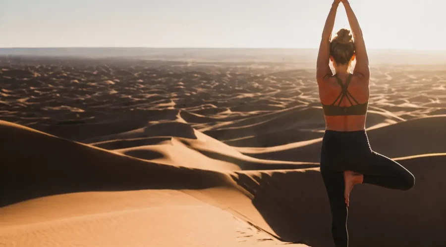 Woman practicing yoga in the Merzouga Sahara Desert during sunrise